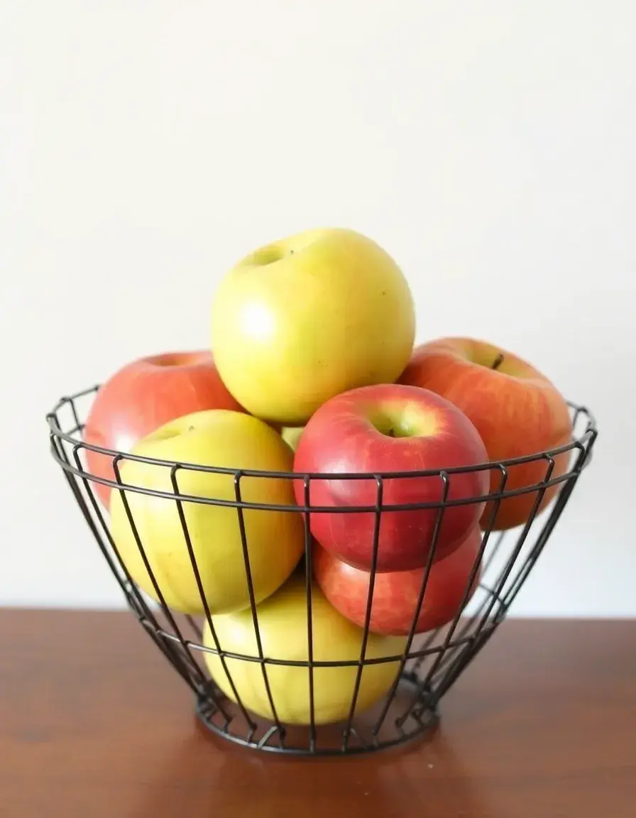 Black metal decorative fruit bowl holding fresh apples on a kitchen counter